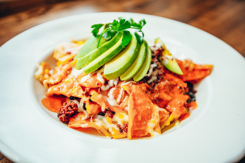 Dish of Chilaquiles topped with sliced avocado