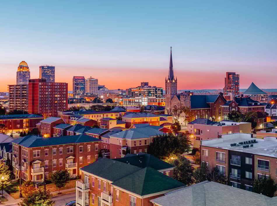 The rooftops of Louisville, Kentucky at night with the glow of a pink sunset.