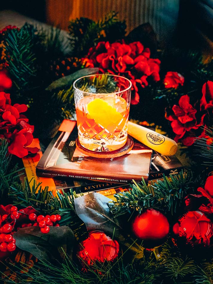 The Old Fashioned cocktail surrounded by Christmas Decor, Kentucky books and a Louisville slugger bat