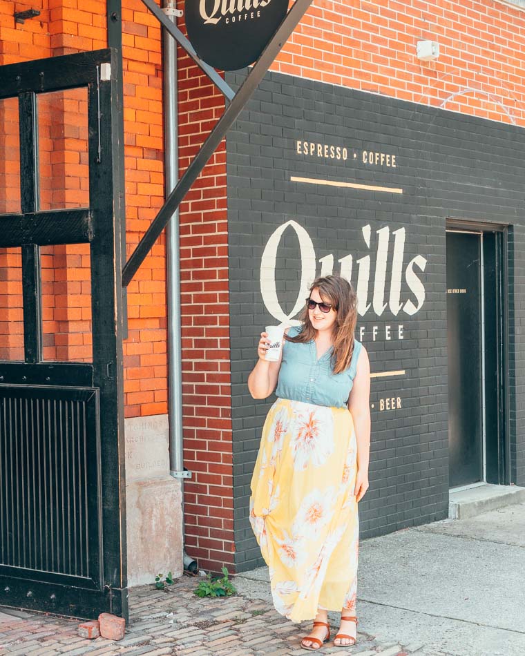 Woman standing with coffee in front of Quills coffee shop in Louisville Ky